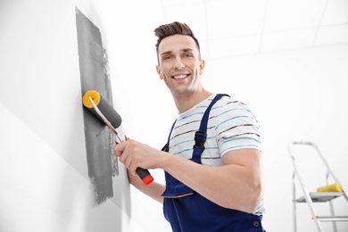 Photo of Young male decorator painting wall in room