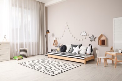 Cute kids room with stylish comfortable floor bed and toys. Montessori interior