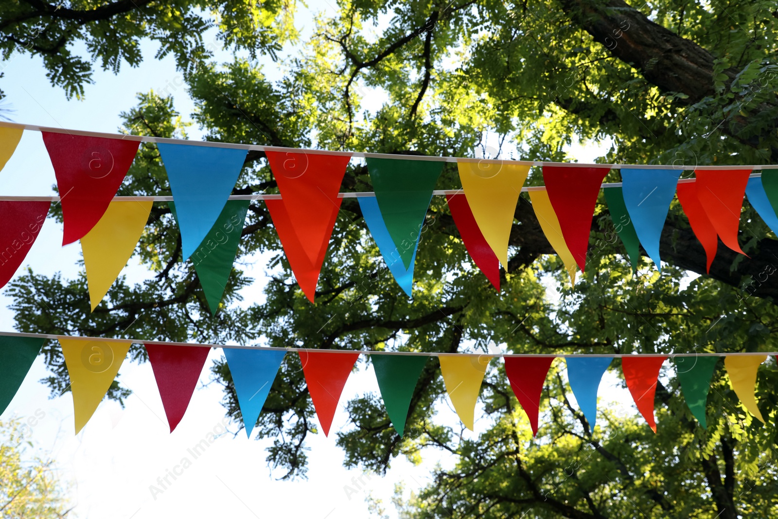 Photo of Colorful bunting flags in park. Party decor