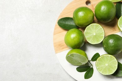 Photo of Fresh ripe limes and leaves on light table, top view. Space for text