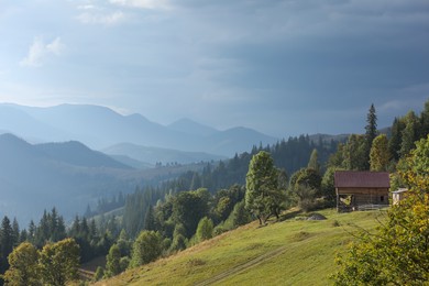 Photo of Beautiful view of wooden house on sunlit green hill in mountains