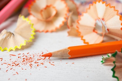Photo of Color pencils and shavings on white table, closeup