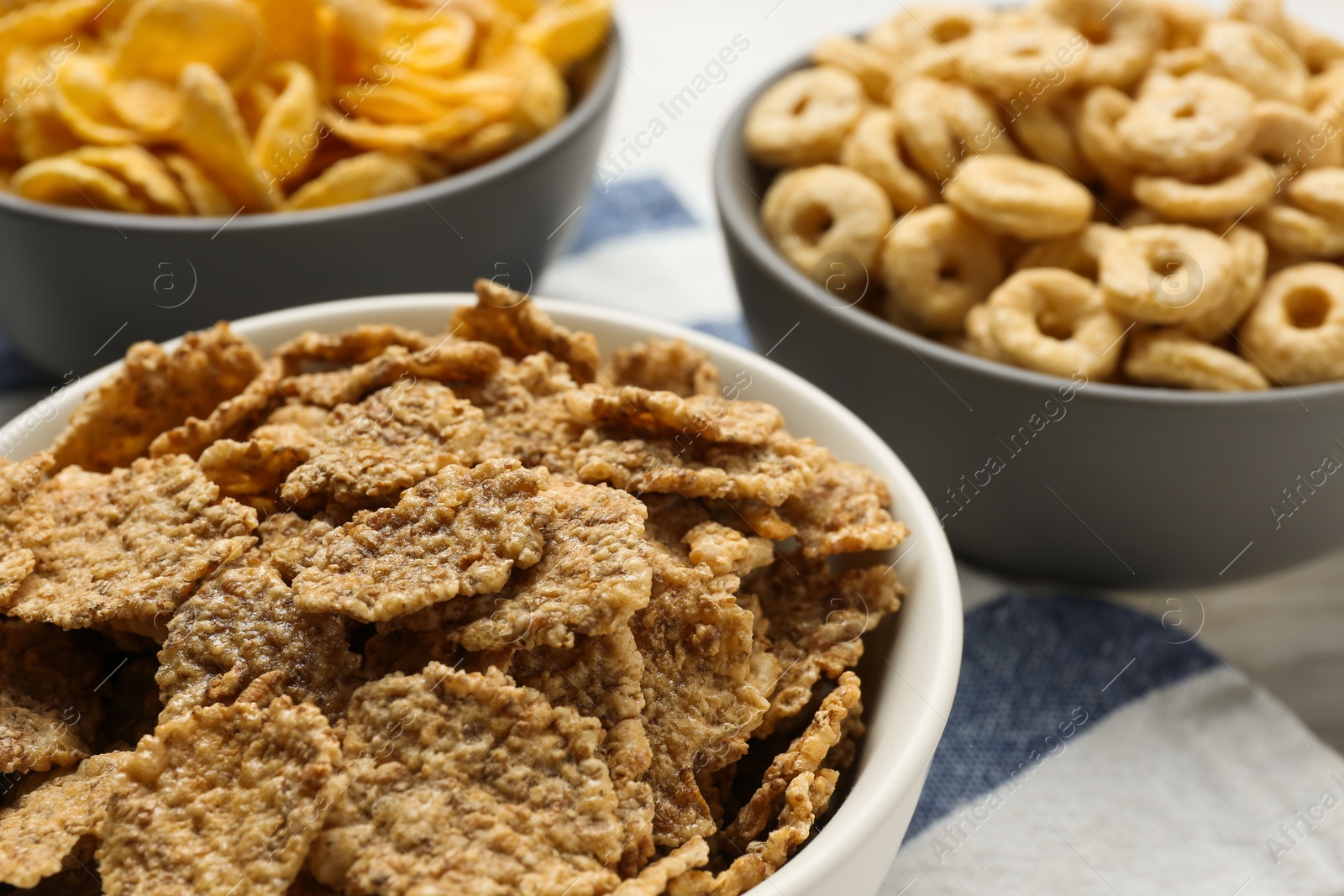 Photo of Different delicious breakfast cereals on kitchen towel, closeup