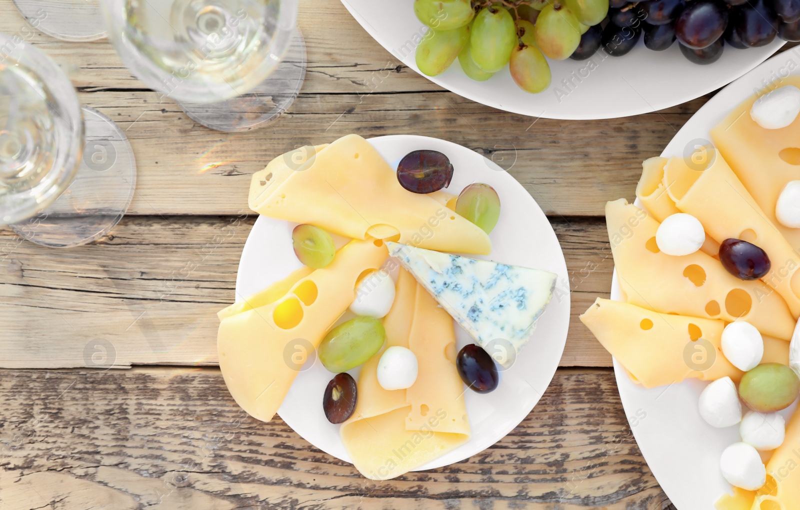 Photo of Wine, cheese and grapes on wooden table, top view. Vineyard picnic