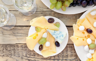 Wine, cheese and grapes on wooden table, top view. Vineyard picnic