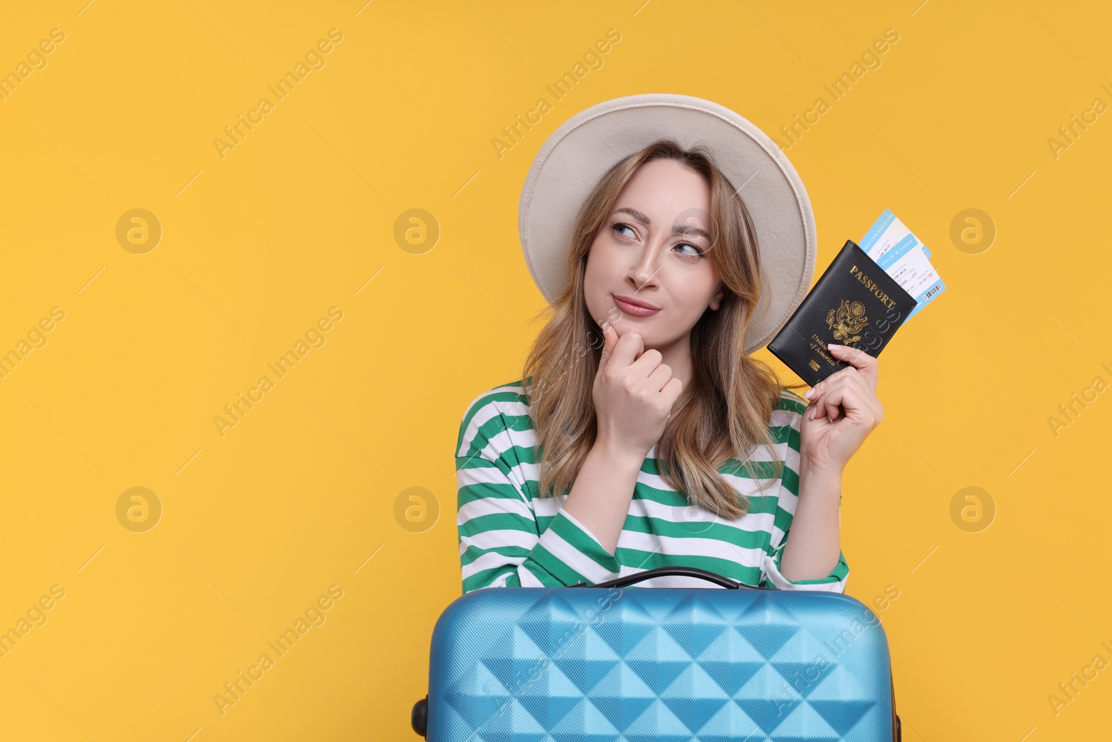 Photo of Young woman with passport, ticket and suitcase on yellow background, space for text