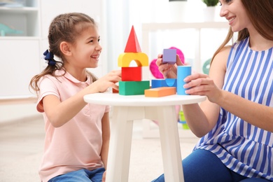 Woman and her child playing with colorful blocks at home