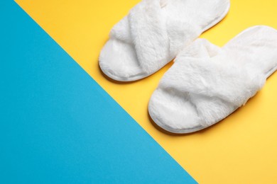 Photo of Pair of soft slippers on color background. Space for text