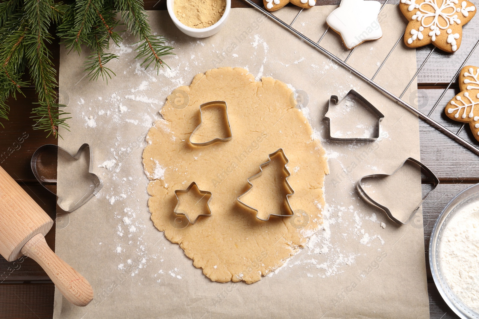 Photo of Making Christmas cookies. Flat lay composition with cutters and raw dough on wooden table