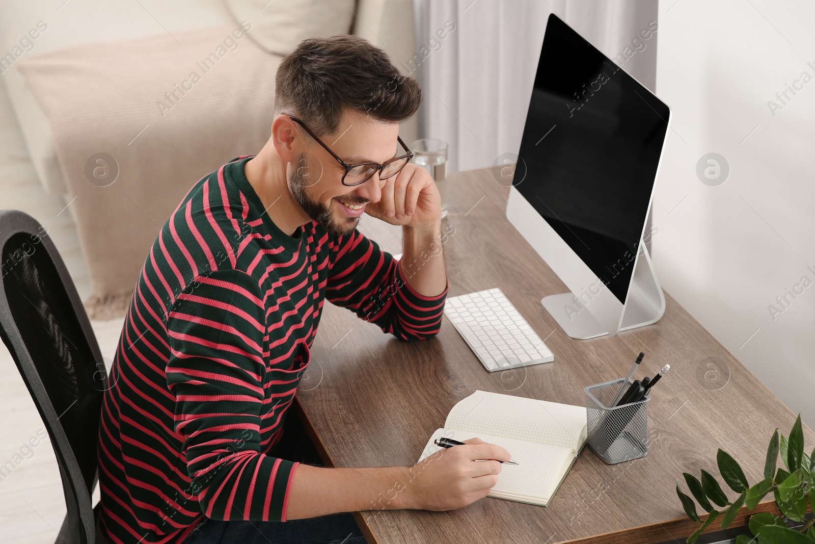 Photo of Man studying near computer at home. Online translation course