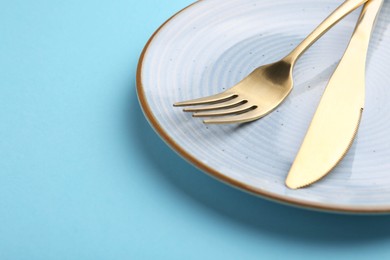 Photo of Setting with stylish cutlery on light blue table, closeup. Space for text