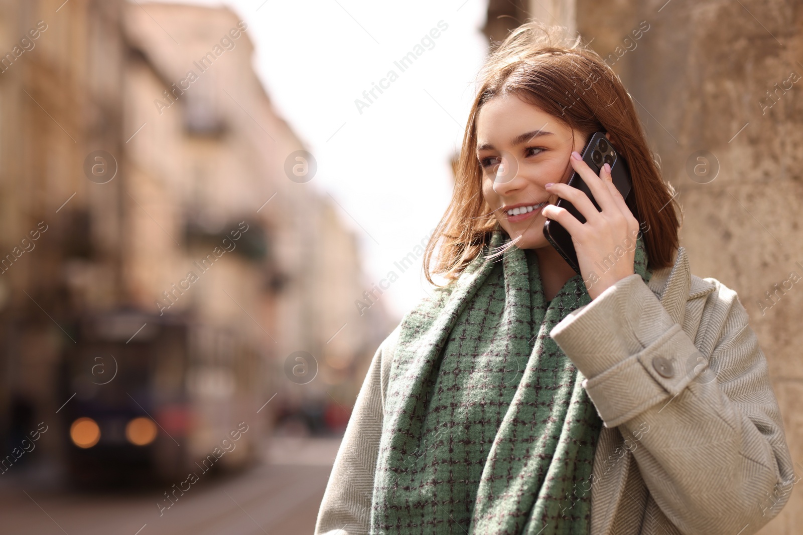Photo of Beautiful woman in warm scarf talking on phone outdoors, space for text