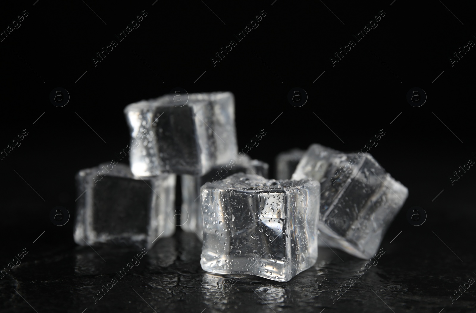 Photo of Ice cubes with water drops on black background, closeup