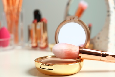 Compact powder and makeup brush on dressing table. Space for text