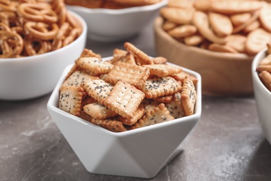 Photo of Delicious crackers in bowls on grey table, closeup