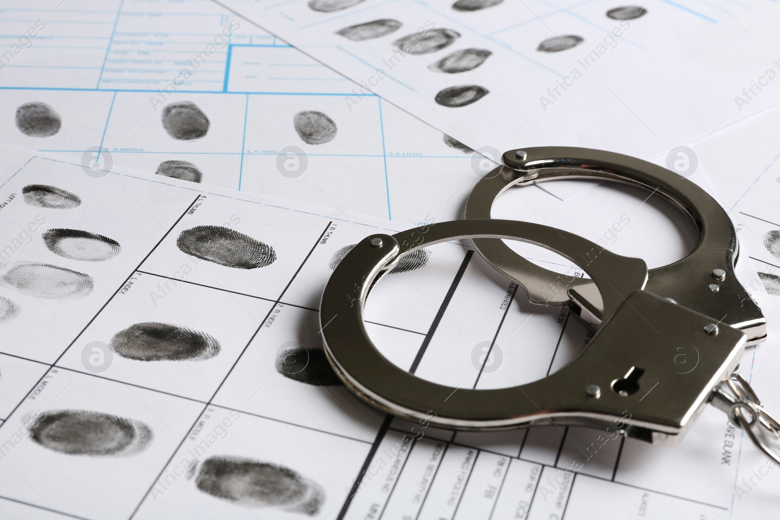 Photo of Handcuffs and fingerprint record sheets, closeup. Criminal investigation