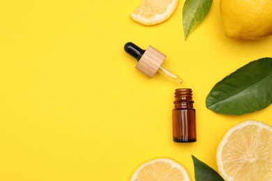Photo of Bottle of citrus essential oil, pipette and fresh lemons on yellow background, flat lay. Space for text