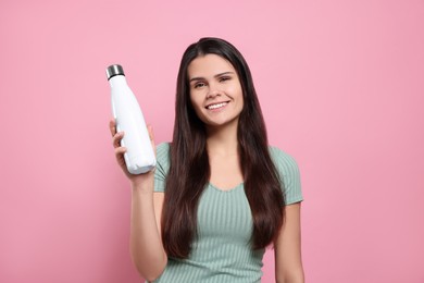 Young woman with thermo bottle on pink background