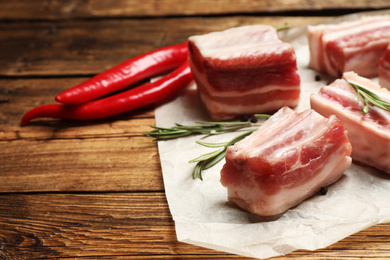 Photo of Raw ribs with rosemary on wooden table, closeup. Space for text