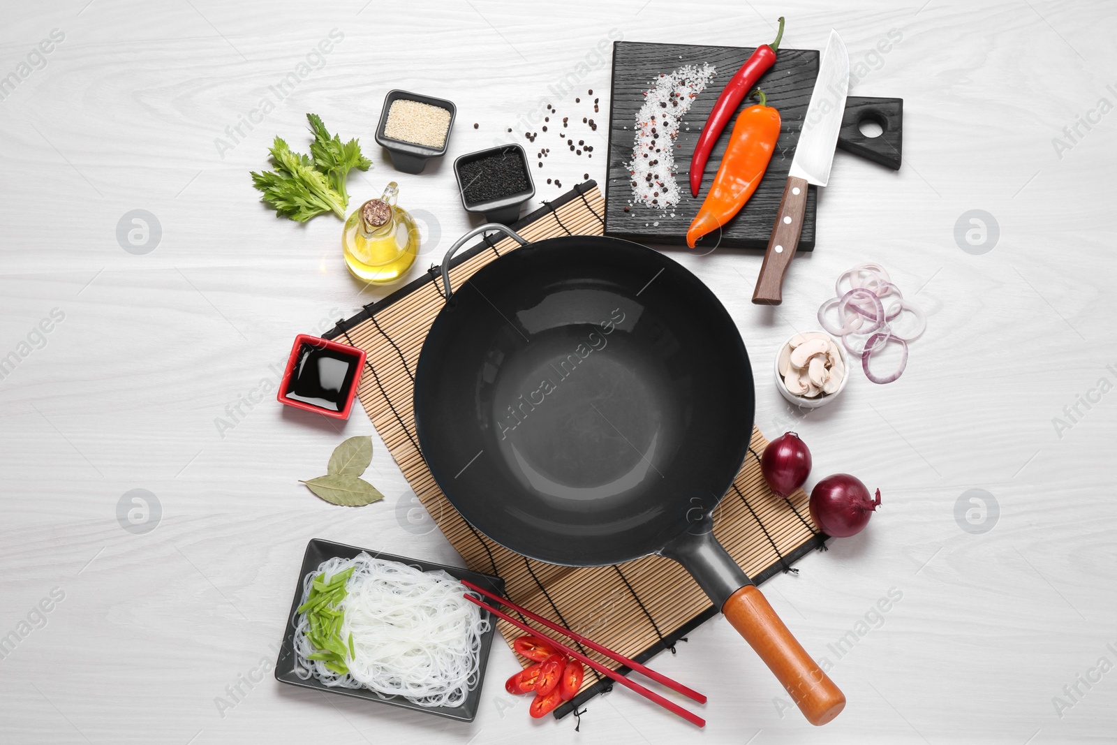 Photo of Wok, chopsticks and different products on white wooden table, flat lay