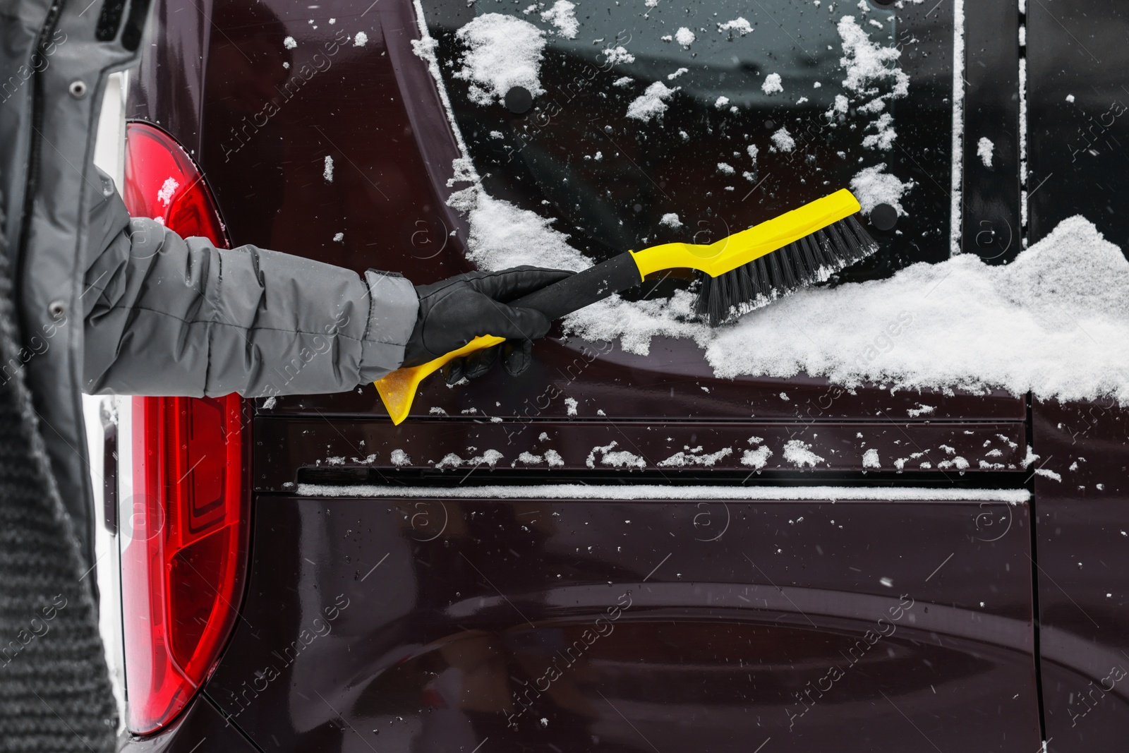 Photo of Man cleaning snow from car window outdoors, closeup