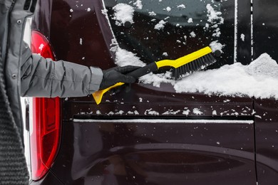 Photo of Man cleaning snow from car window outdoors, closeup