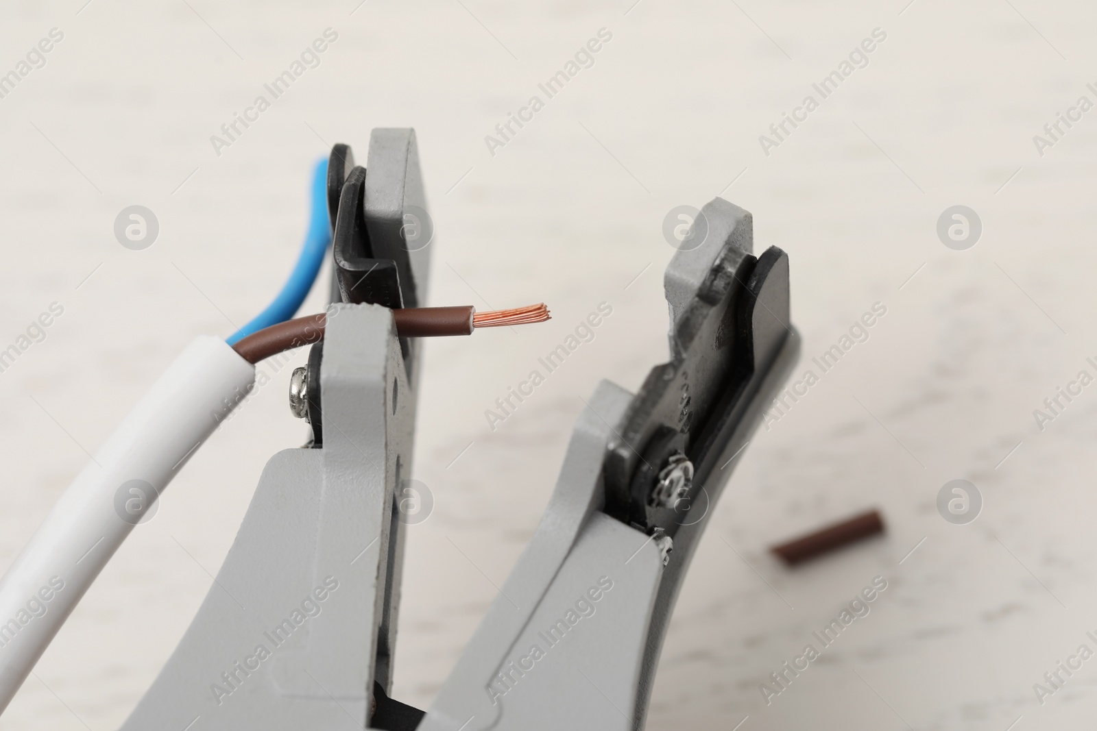 Photo of Cutters and stripped wire on white wooden table, closeup