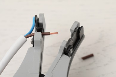 Photo of Cutters and stripped wire on white wooden table, closeup