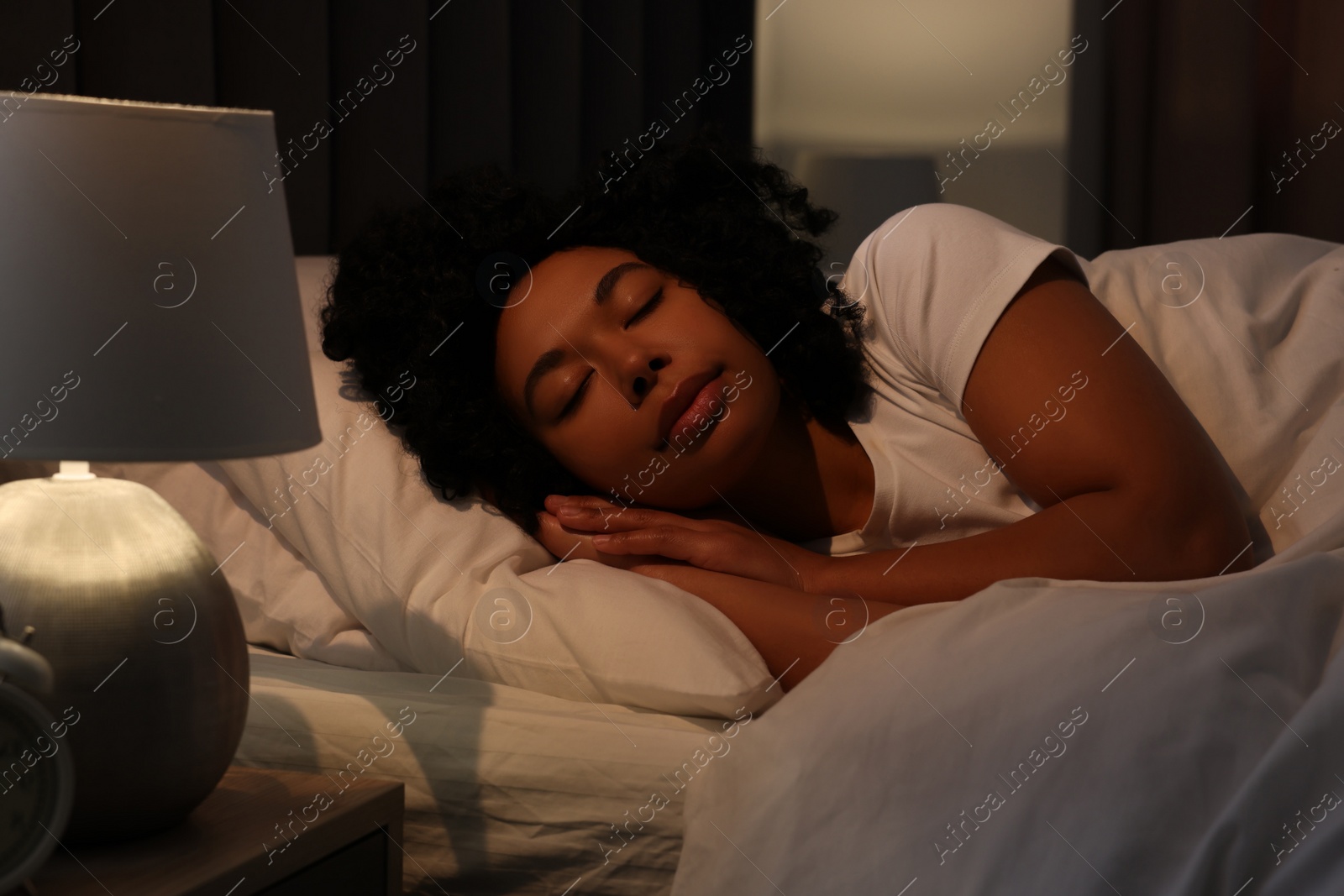 Photo of Young woman sleeping in soft bed at night