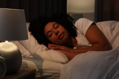 Photo of Young woman sleeping in soft bed at night