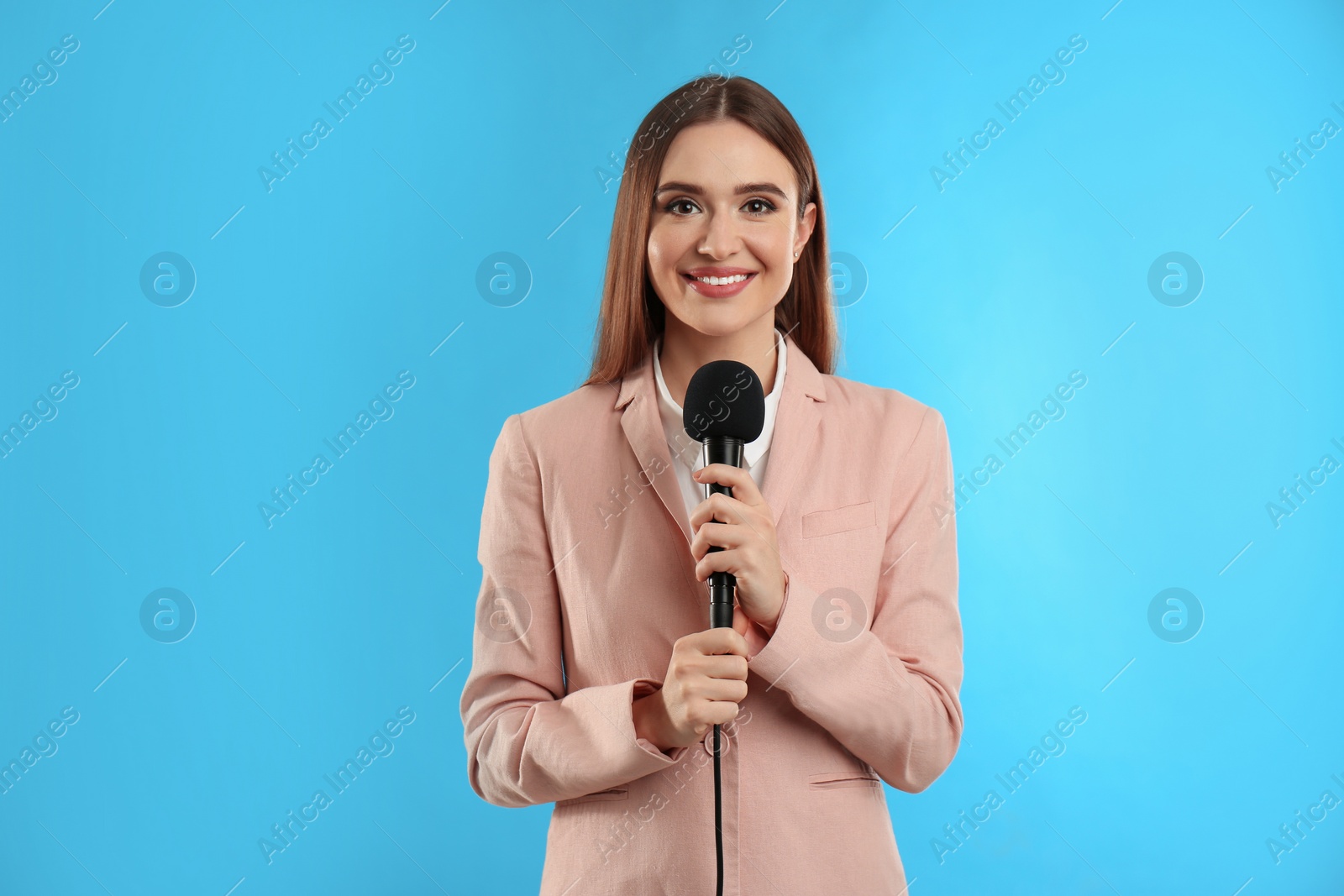 Photo of Young female journalist with microphone on blue background