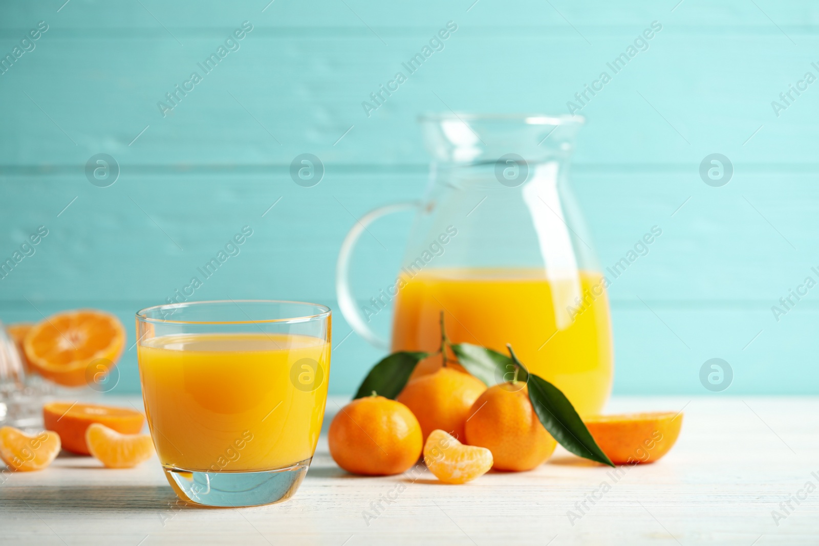 Photo of Glass of fresh tangerine juice and fruits on white wooden table