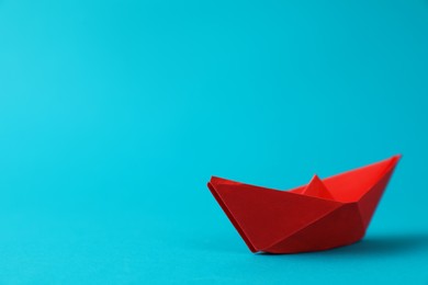 Handmade red paper boat on light blue background. Space for text