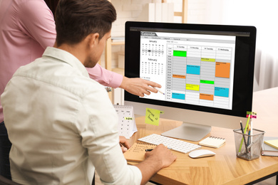 Colleagues working with calendar app on computer in office