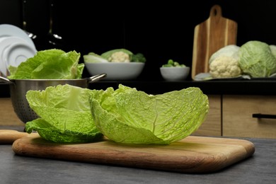 Photo of Fresh Savoy cabbage leaves on black table in kitchen