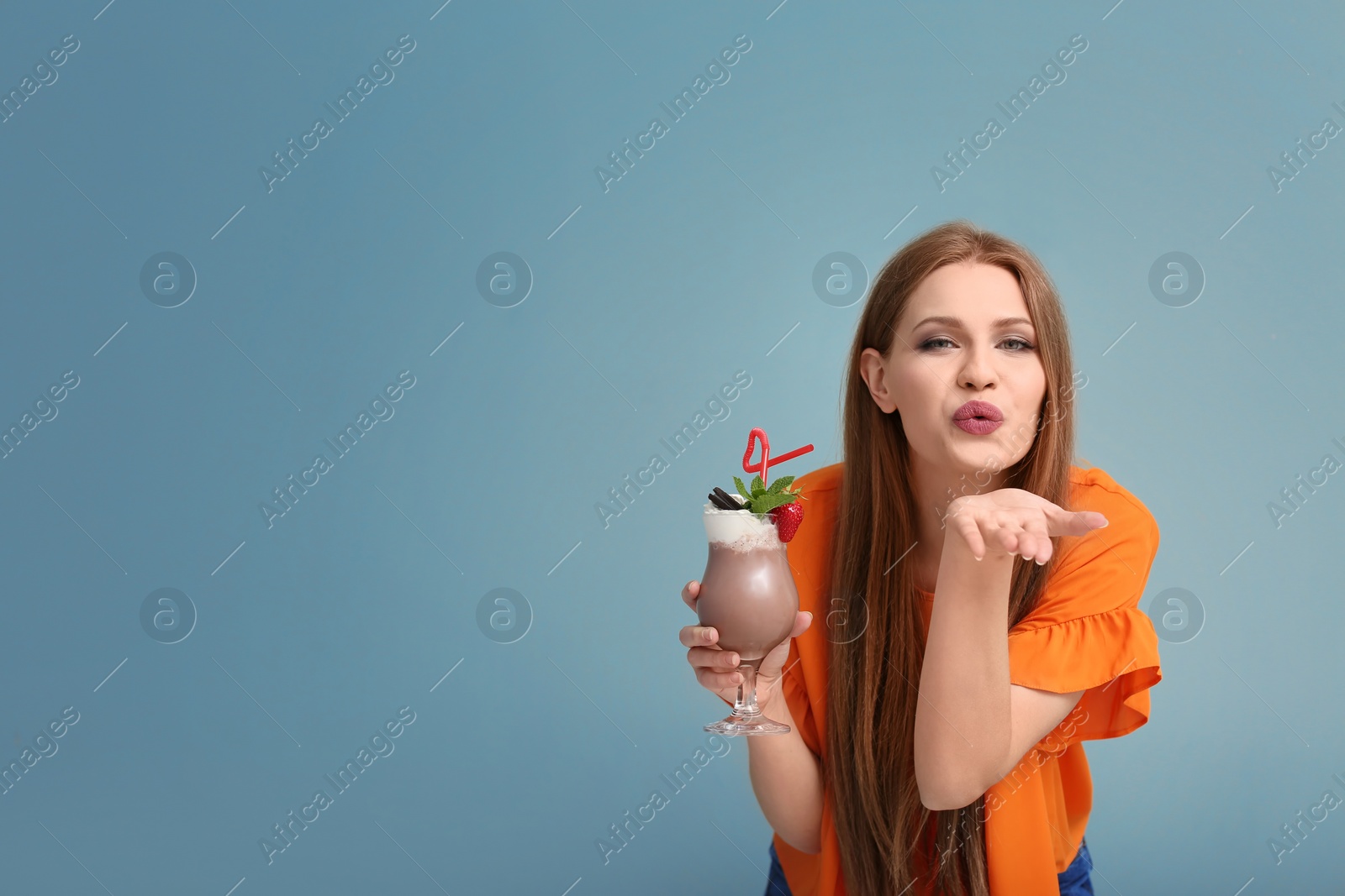 Photo of Young woman with glass of delicious milk shake on color background