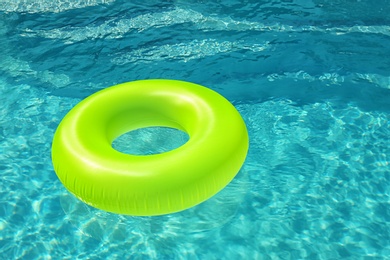 Bright inflatable ring floating in swimming pool on sunny day. Space for text