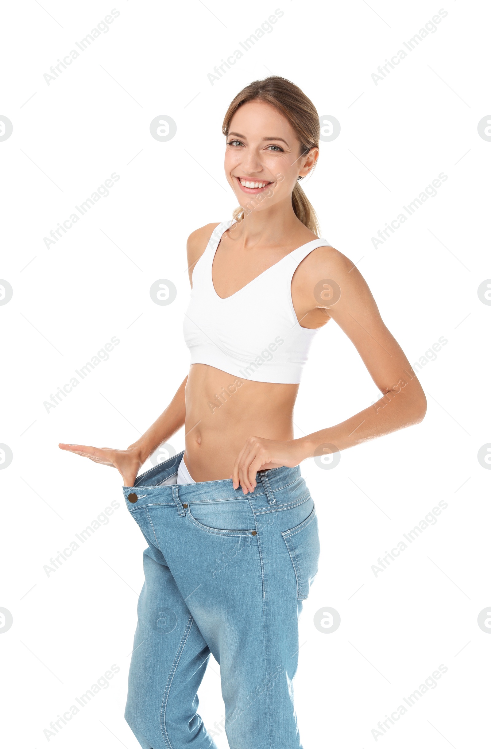 Photo of Young slim woman in old big jeans showing her diet results on white background