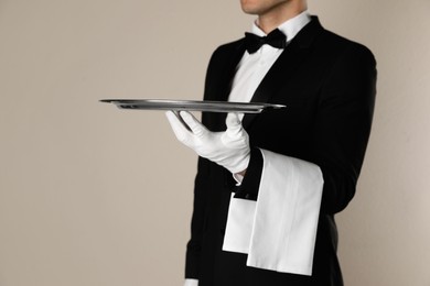 Butler with tray on beige background, closeup. Space for text