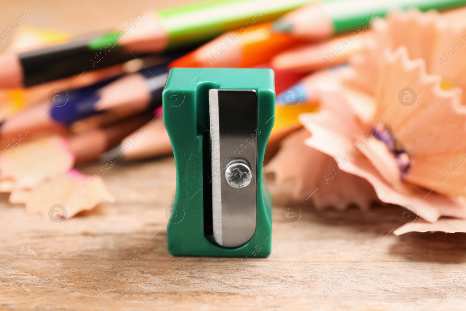 Photo of Turquoise sharpener, pencils and shavings on wooden table, closeup