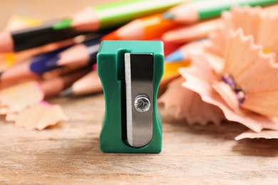 Photo of Turquoise sharpener, pencils and shavings on wooden table, closeup