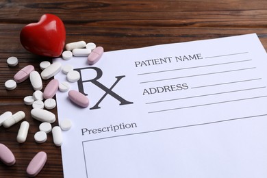 Photo of Medical prescription form with empty fields, red heart and pills on wooden table