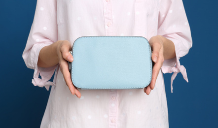Photo of Young woman with stylish bag on blue background, closeup
