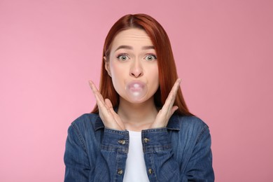 Photo of Surprised woman blowing bubble gum on pink background