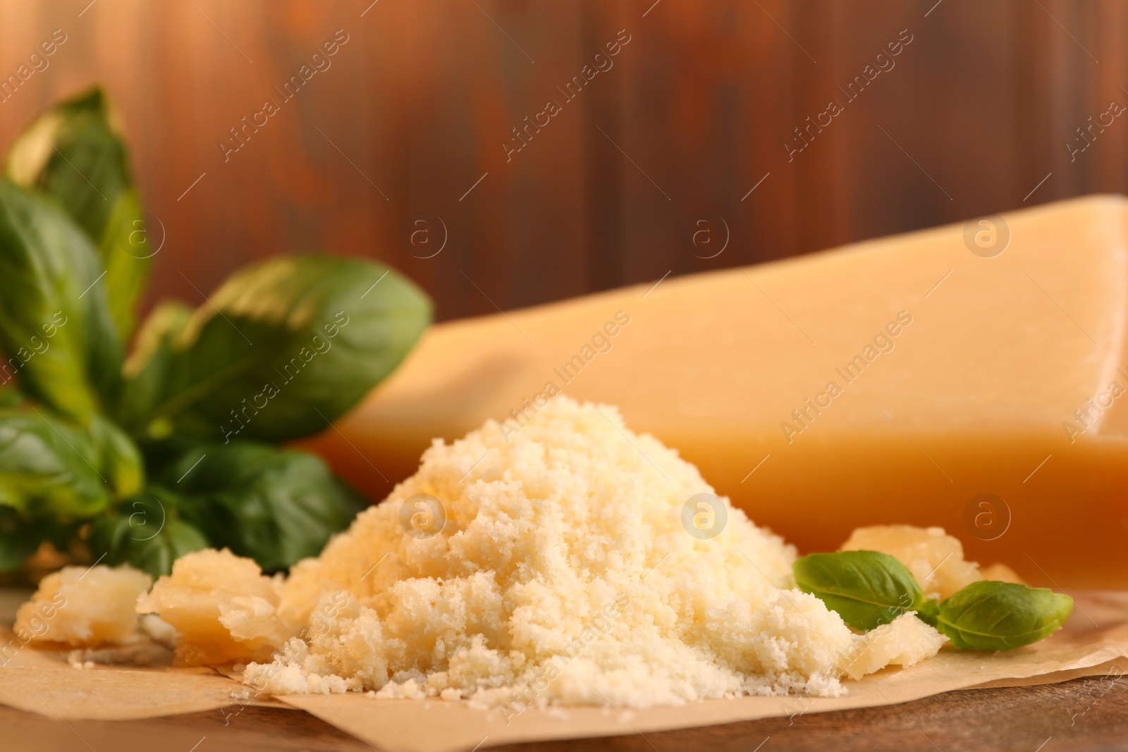 Photo of Delicious grated parmesan cheese and basil on parchment paper, closeup