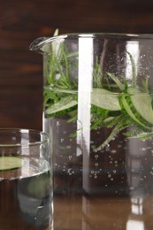 Photo of Refreshing cucumber water with rosemary in jug and glass, closeup