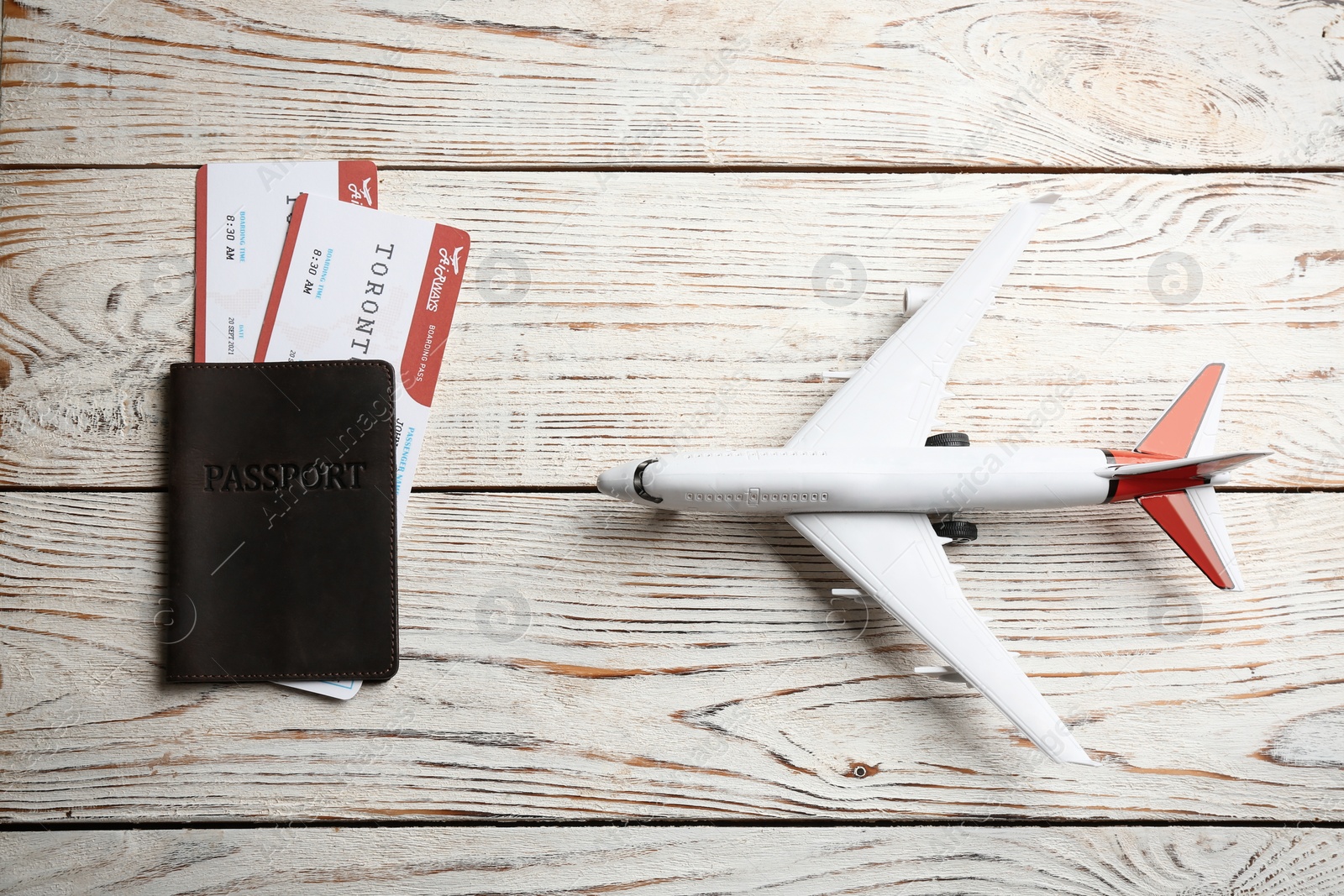 Photo of Toy airplane and passport with tickets on white wooden background, flat lay