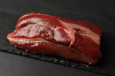 Photo of Piece of raw beef meat on black table, closeup