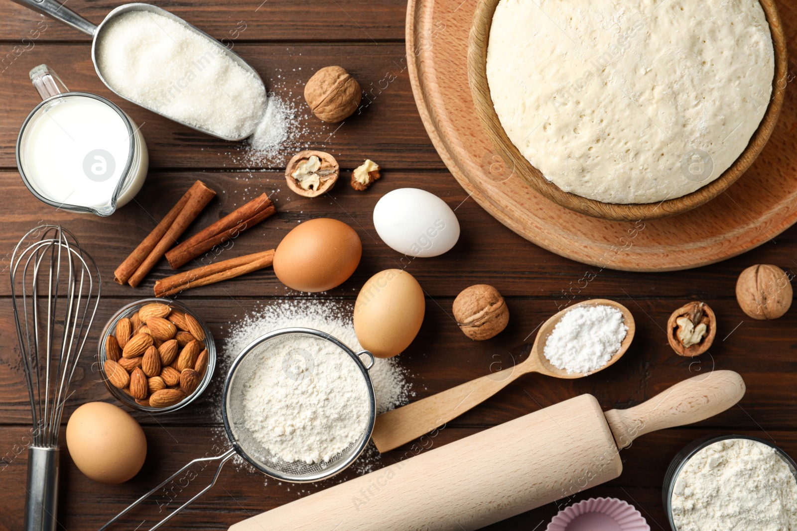 Photo of Dough and ingredients for pastries on wooden table, flat lay