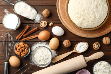 Dough and ingredients for pastries on wooden table, flat lay